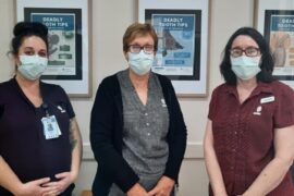 Jess, Narelle and Lesley from the MDHS Dental Service Team standing in front of a wall with tops on how to look after teeth