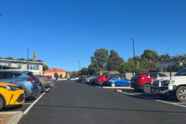 A newly constructed asphalt car park at a hospital is filled cars