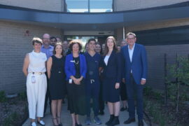 Victorian Member Dan Andrews stands with a group of healthcare professionals in front of the entrance to a new 2-storey building.