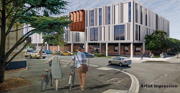 An artist's impression of a new modern hospital and streetscape with a view from the corner. There are two people walking their bikes in the fore-ground.