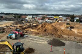 Aerial view of a construction site for a new hospital showing earth moving equipment among piles of dirt