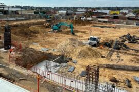 A large hole in the ground is filled with concrete on the site of a new hospital