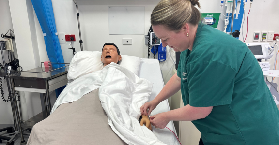 Louise practicing administration of therapy on a dummy in a sim lab