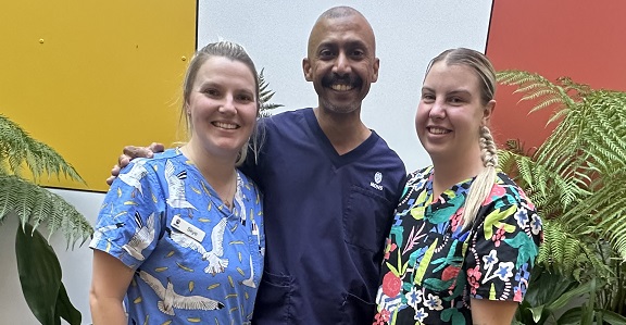 Three Registered Nurse Graduates stand in a courtyard.