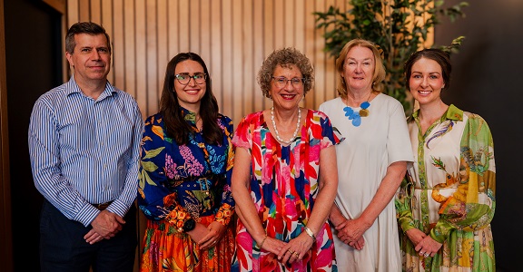 Five board members standing in a row smiling