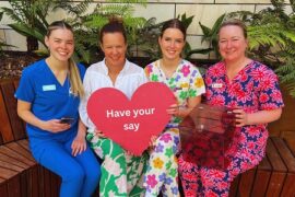A health service CEO and three nurses in coloured scrubs sit in a courtyard.